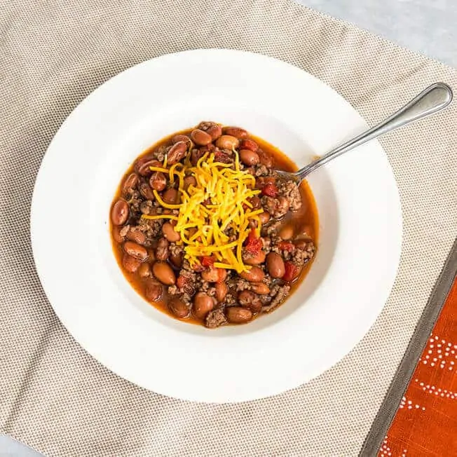 beef and bean chili in a whilte bowl with a natural placemat