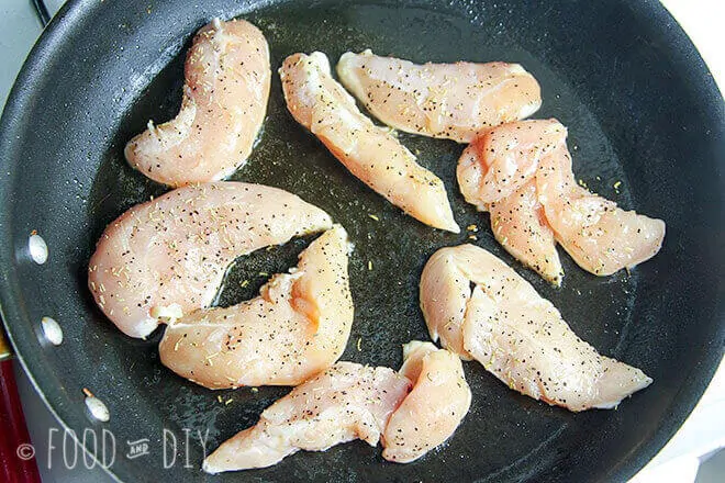 Chicken tenders cooking in olive oil in a skillet