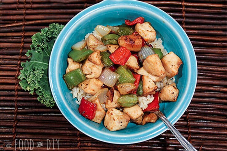 Ginger chicken stir fry in bowl on bamboo placemat