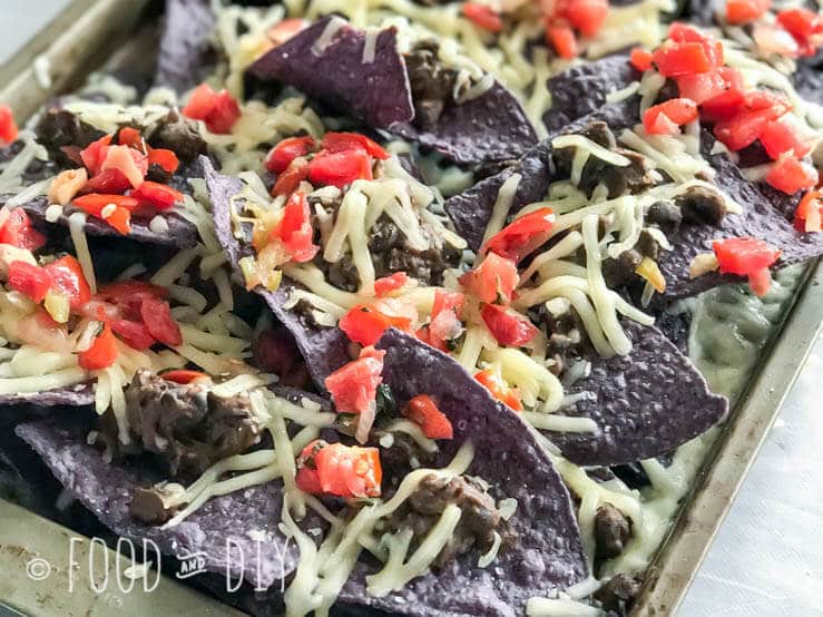 Baked Black Bean Nachos. Layers of crisp blue corn chips, Monterey Jack cheese, refried black beans, and topped with pico de gallo. Delicious.
