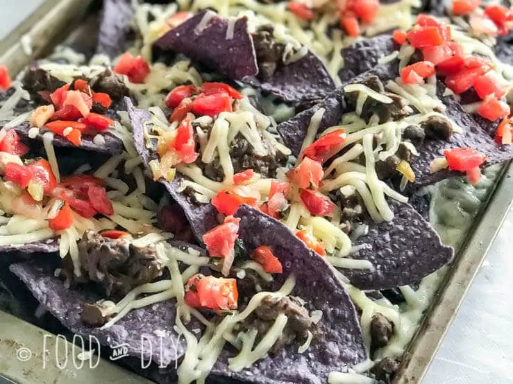 Baked Black Bean Nachos. Layers of crisp blue corn chips, Monterey Jack cheese, refried black beans, and topped with pico de gallo. Delicious.