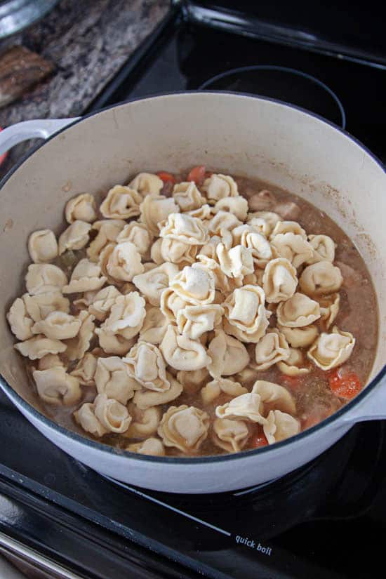 cheese tortellini and vegetables in chicken broth in dutch oven
